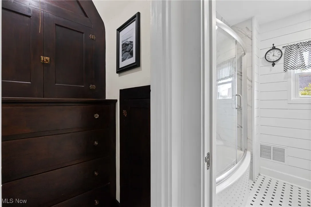 Full bath featuring plenty of natural light and a marble finish shower