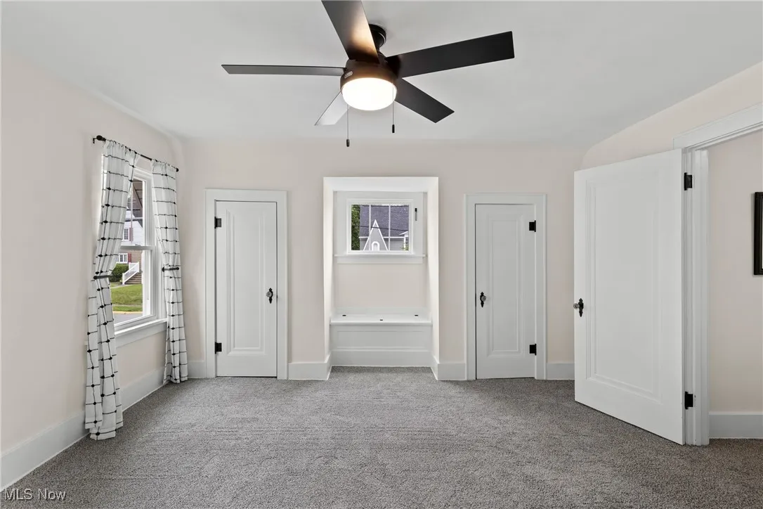 Unfurnished bedroom featuring carpet floors, multiple closets, and ceiling fan