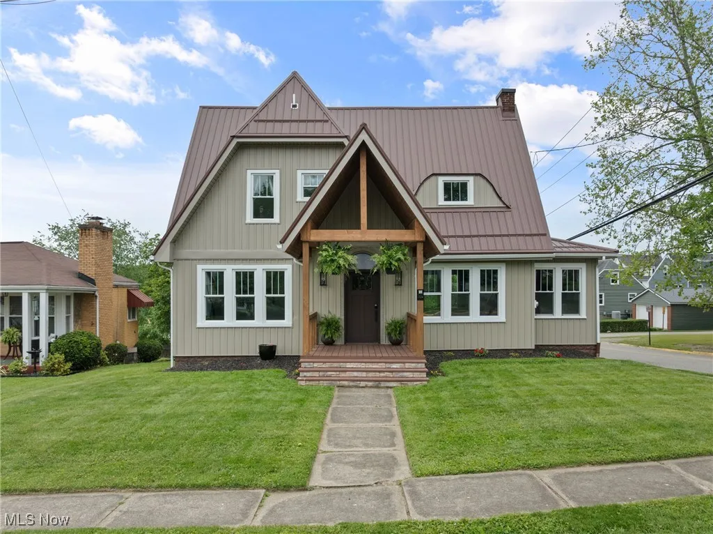 View of front of house featuring a front lawn, a chimney, a metal roof, and board and batten siding