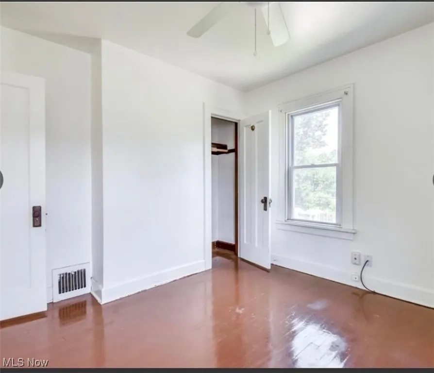 Unfurnished bedroom with dark wood-type flooring, a ceiling fan, and a closet