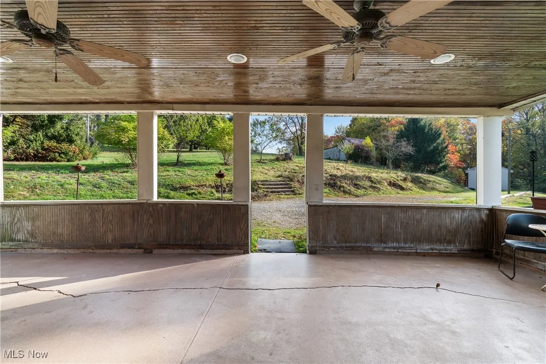 Unfurnished sunroom with ceiling fan and a patio area