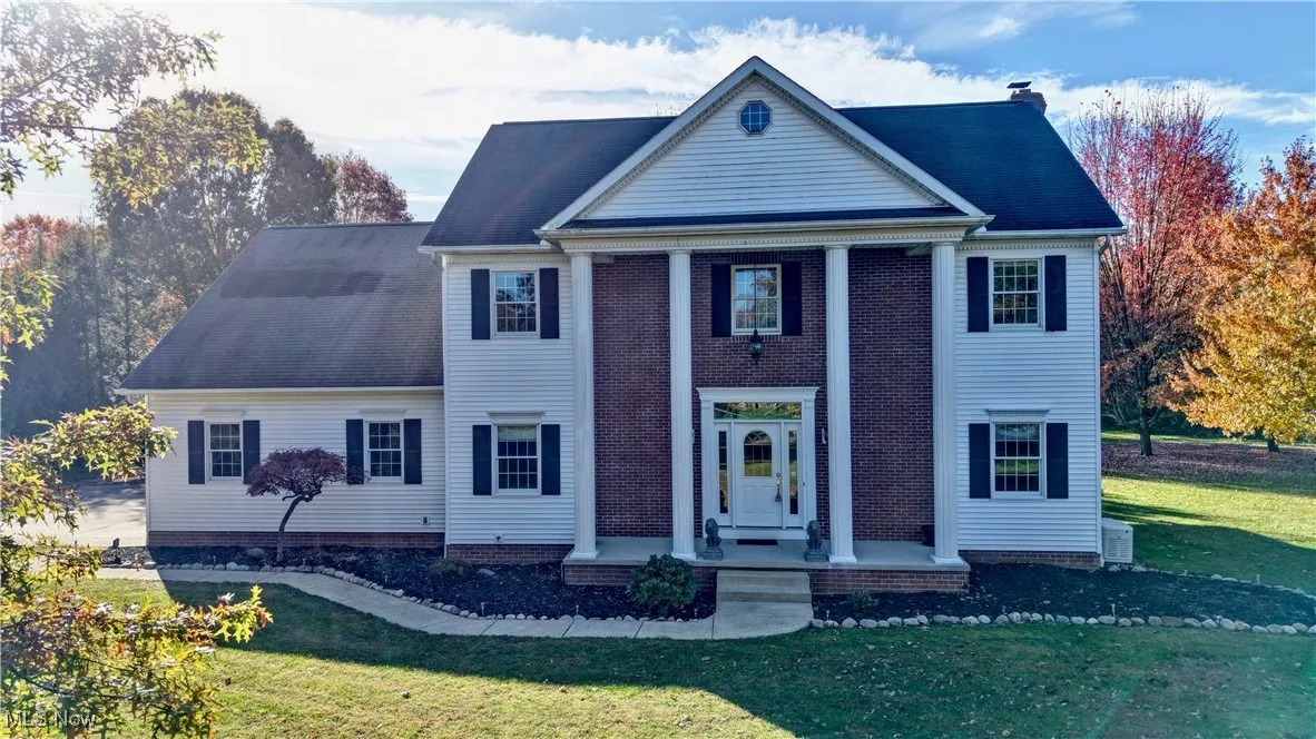 Neoclassical / greek revival house with a front yard and a chimney