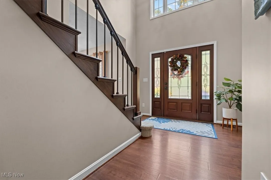 Entryway featuring wood finished floors, a towering ceiling, and stairway