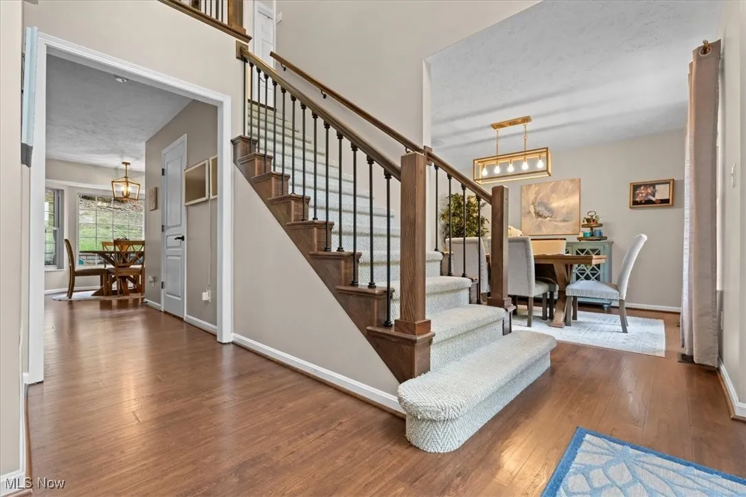 Stairs with a chandelier, a textured ceiling, and wood finished floors