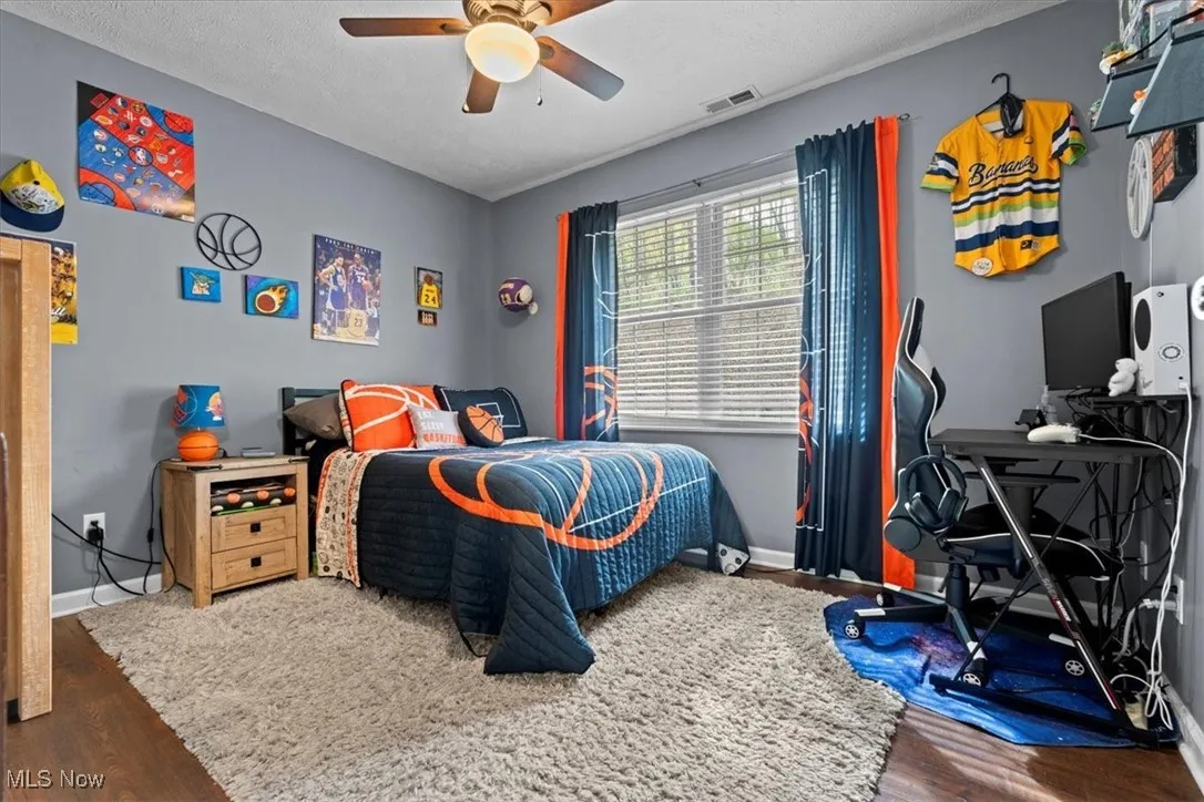 Bedroom with dark wood-type flooring, a ceiling fan, an office area, and a textured ceiling