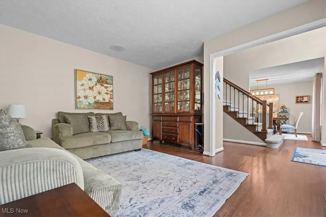 Living room featuring dark wood-style flooring, a textured ceiling, and a chandelier