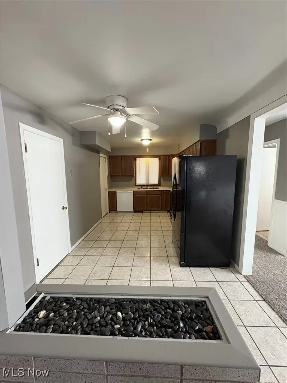 Kitchen with refrigerator, a ceiling fan, white dishwasher, light tile patterned floors, and light countertops