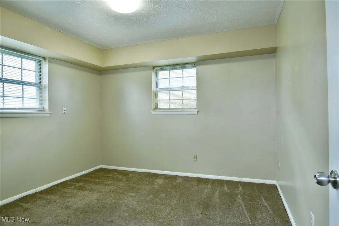 Empty room with dark colored carpet and a textured ceiling