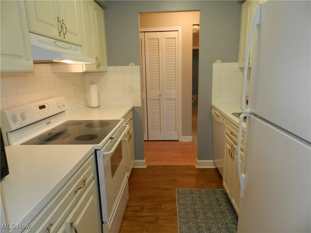 Kitchen featuring white appliances, light countertops, and decorative backsplash