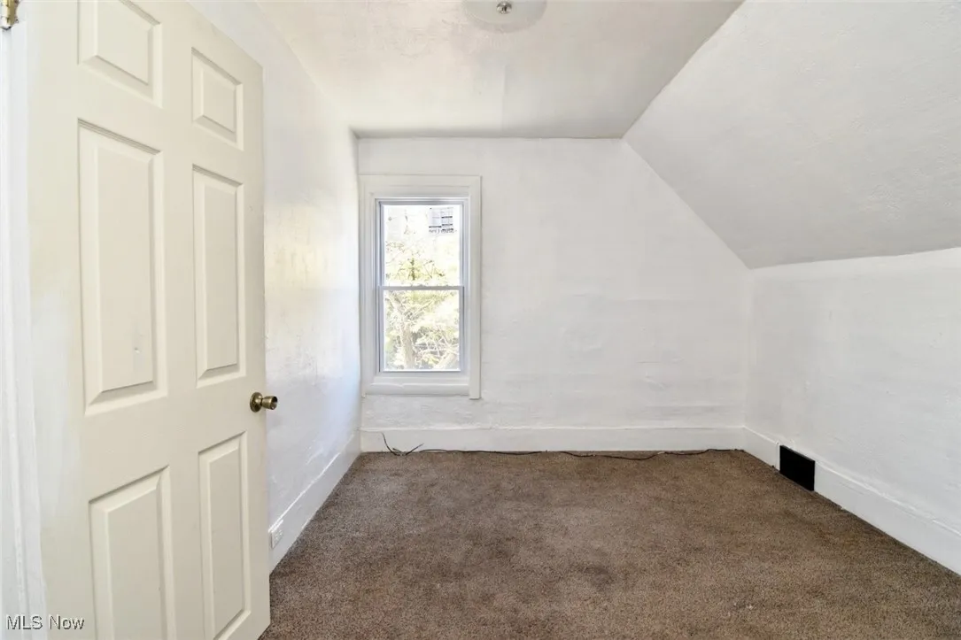 Additional living space with carpet flooring and vaulted ceiling
