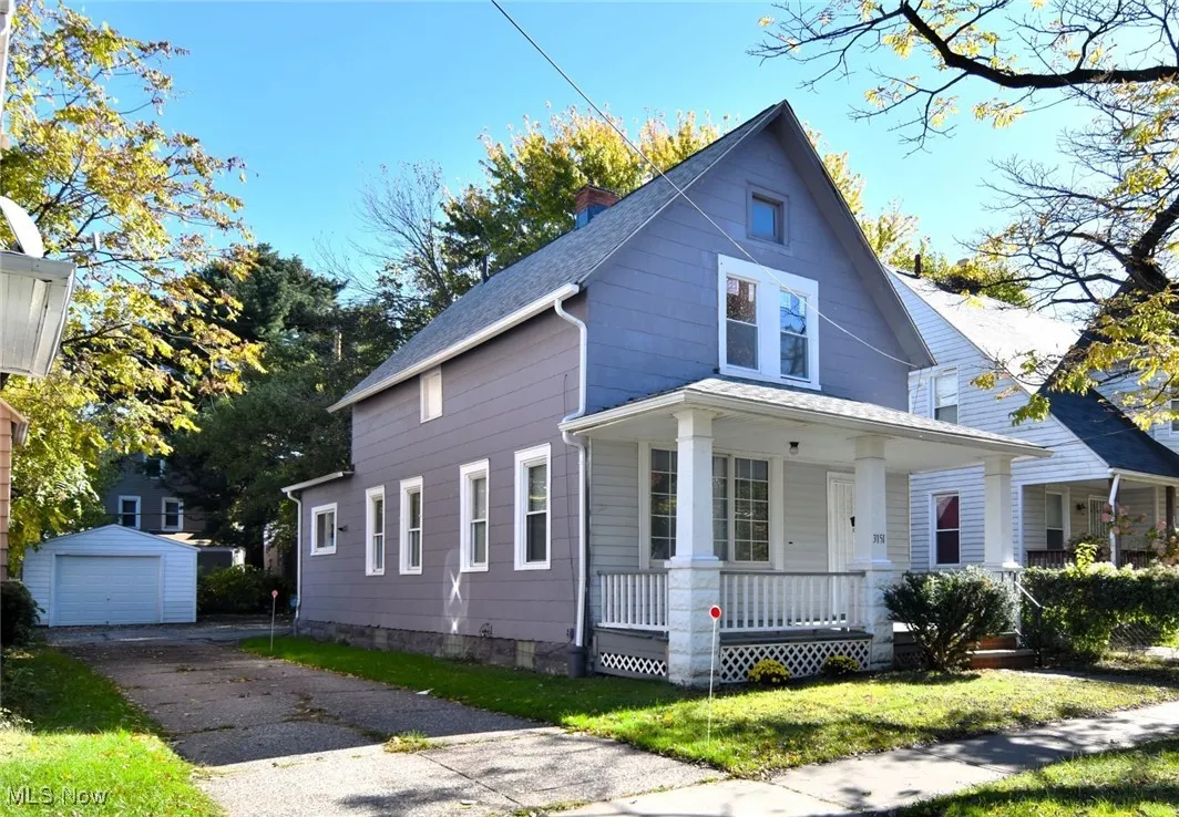 View of front of home featuring a porch, a chimney, an outdoor structure, a front yard, and a garage