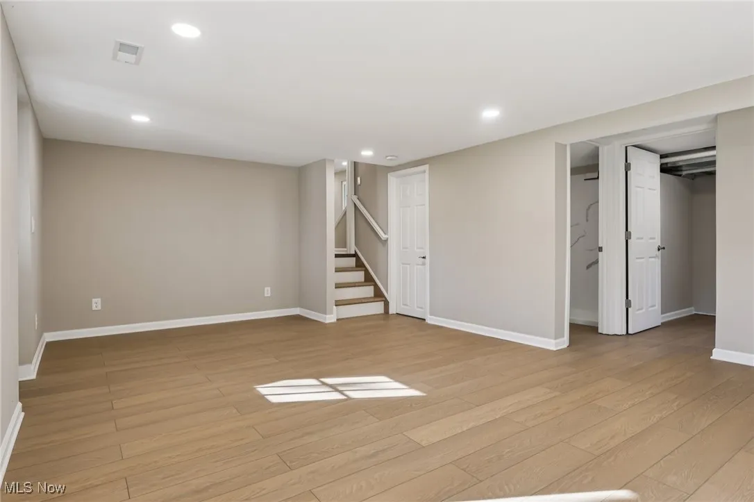 Below grade area with recessed lighting, light wood finished floors, and stairs