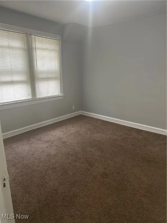 Spare room with dark carpet and baseboards