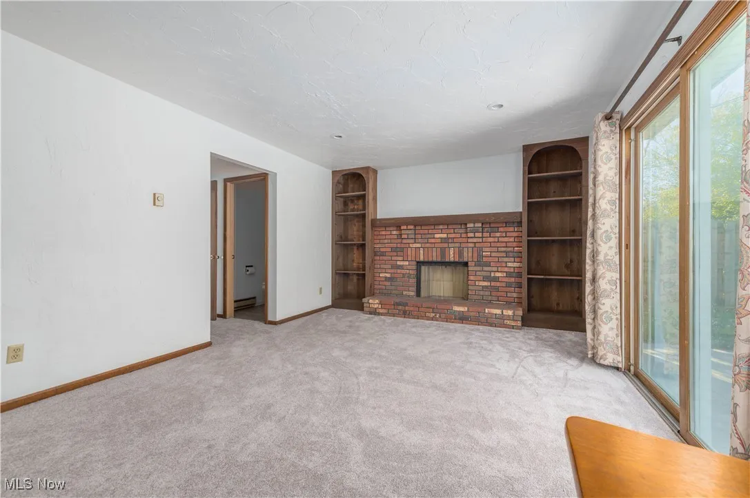Unfurnished living room with built in shelves, a fireplace, carpet flooring, and a textured ceiling