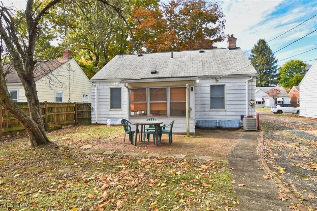 Back of house featuring a sunroom, a patio, a chimney, and a shingled roof