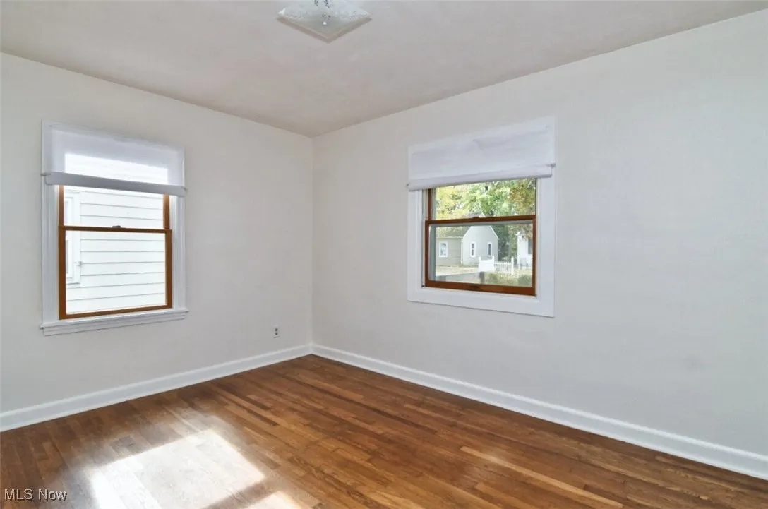 Spare room featuring baseboards and dark wood finished floors