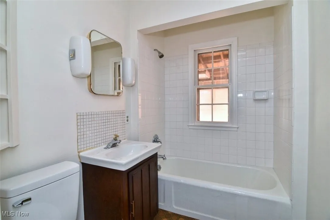 Bathroom with shower / tub combination, vanity, and backsplash