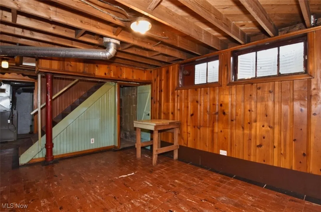 Basement featuring wood walls, heating unit, and stairway
