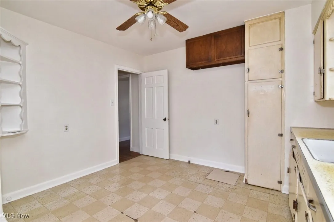 Kitchen featuring light floors, light countertops, open shelves, and a ceiling fan