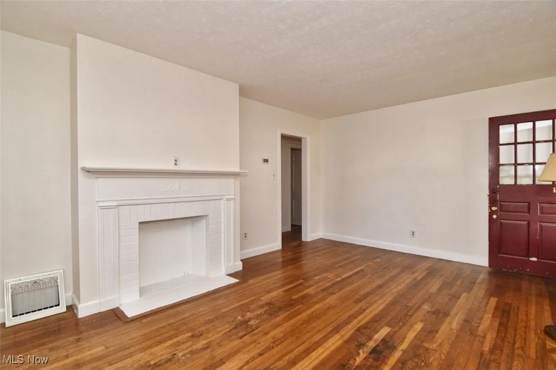 Unfurnished living room with heating unit, dark wood-type flooring, and a textured ceiling