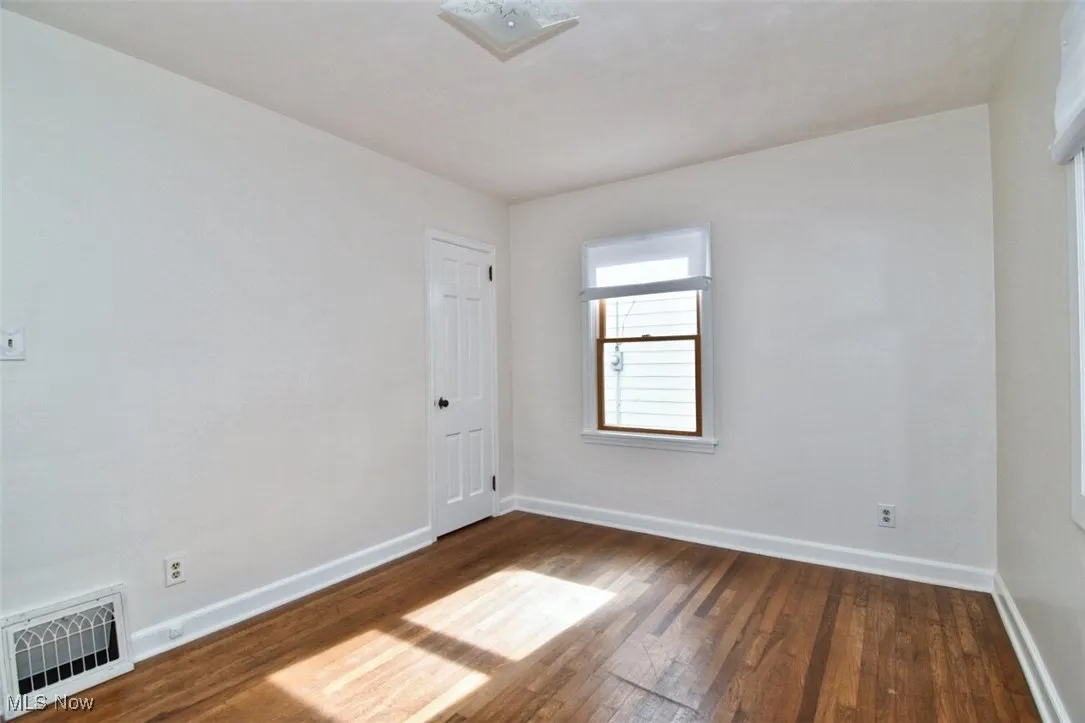 Unfurnished room with dark wood-type flooring and baseboards