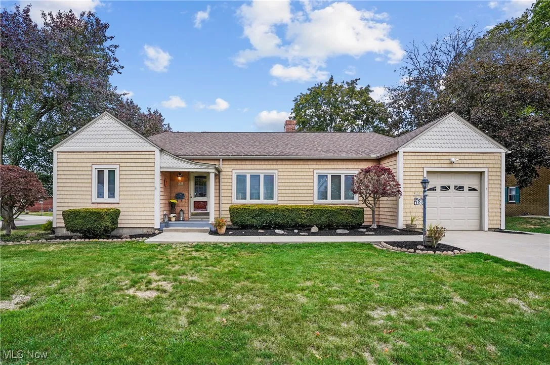 Ranch-style home featuring a front lawn, a garage, and roof with shingles