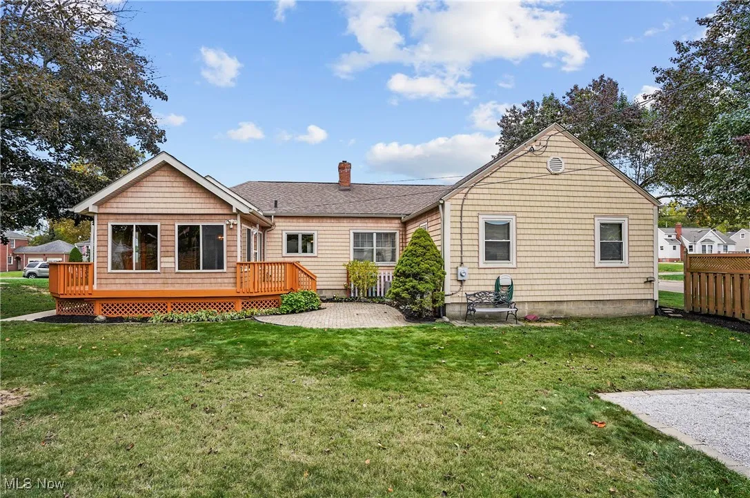 Back of house with a deck, a lawn, and a chimney
