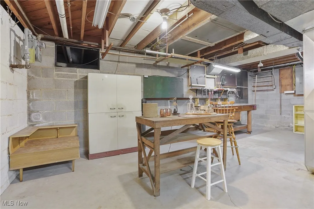 Unfinished basement with a workshop area and electric panel