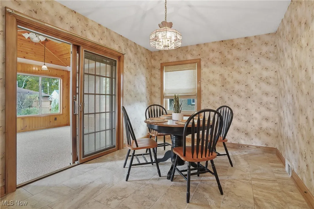 Dining room with wallpapered walls and a chandelier