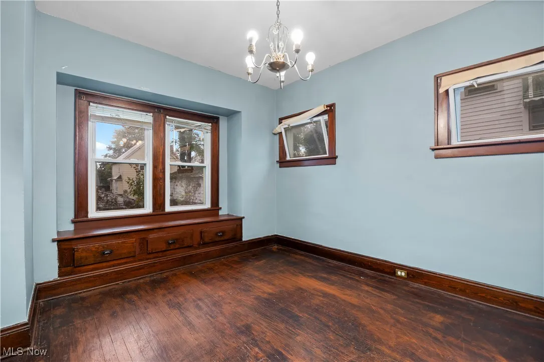 Unfurnished room featuring hardwood / wood-style floors and a chandelier