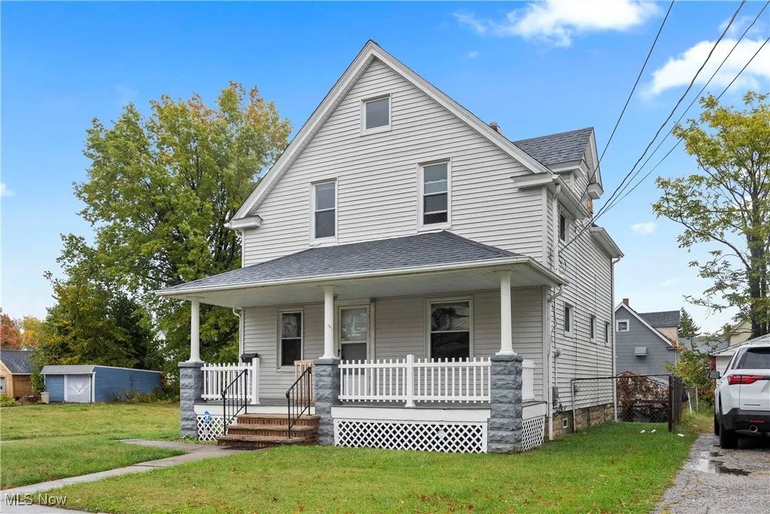 View of front of home featuring a front yard, covered porch, and a shingled roof