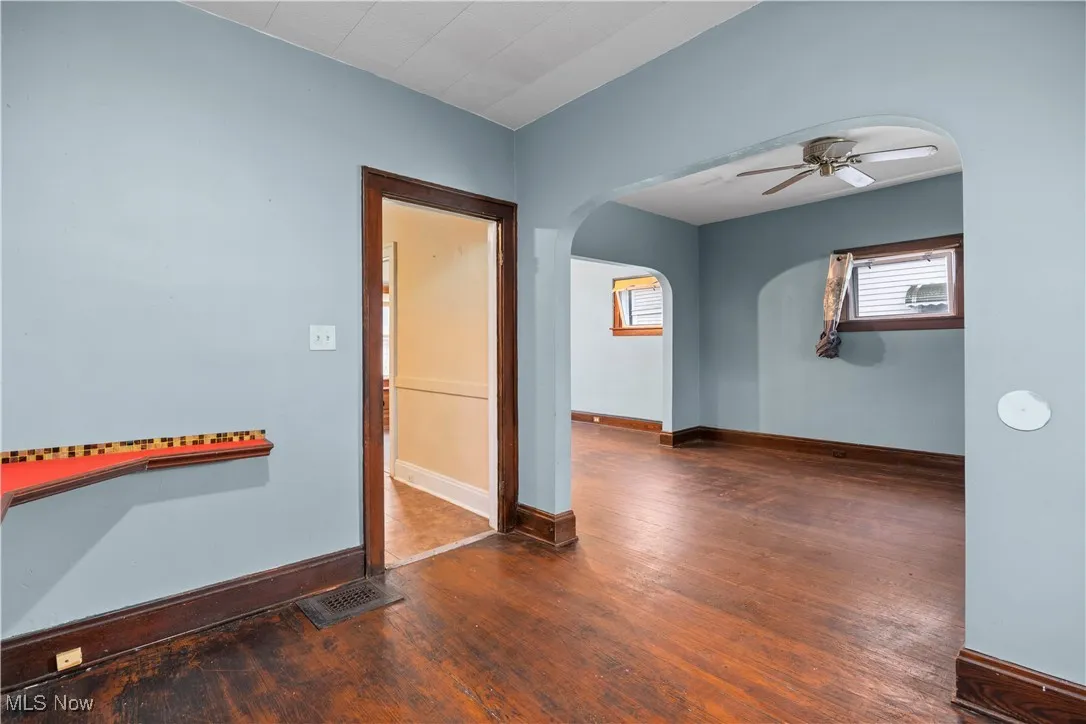Spare room featuring arched walkways, ceiling fan, and dark wood finished floors