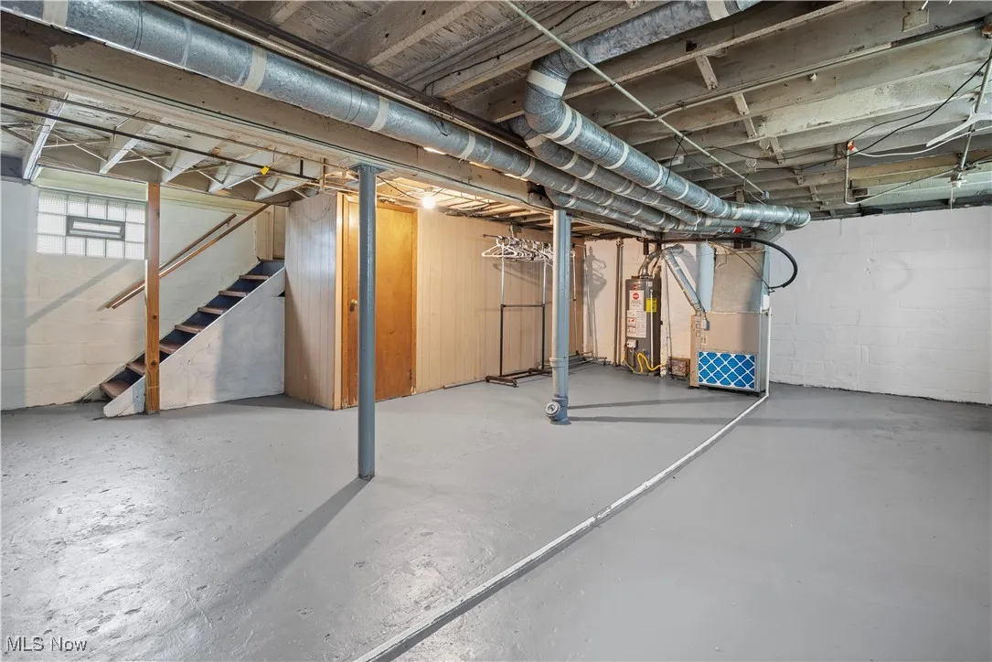 Below grade area with stairs, heating unit, and water heater