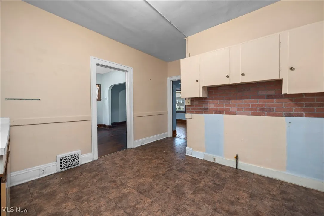 Kitchen featuring arched walkways and white cabinetry