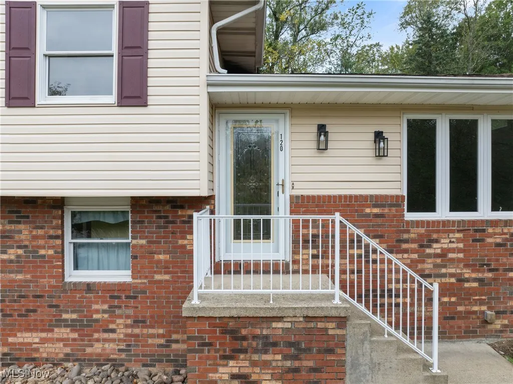 Doorway to property with brick veneer, and siding