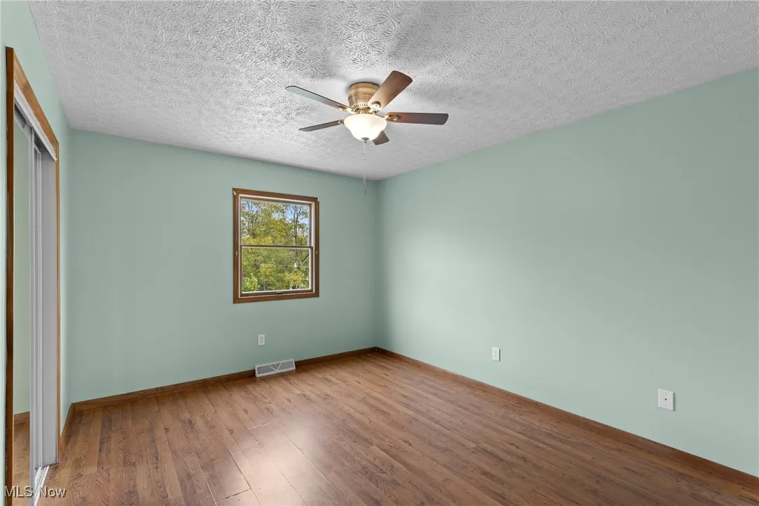 Unfurnished bedroom with wood style finished floors, a closet, a ceiling fan, and a textured ceiling