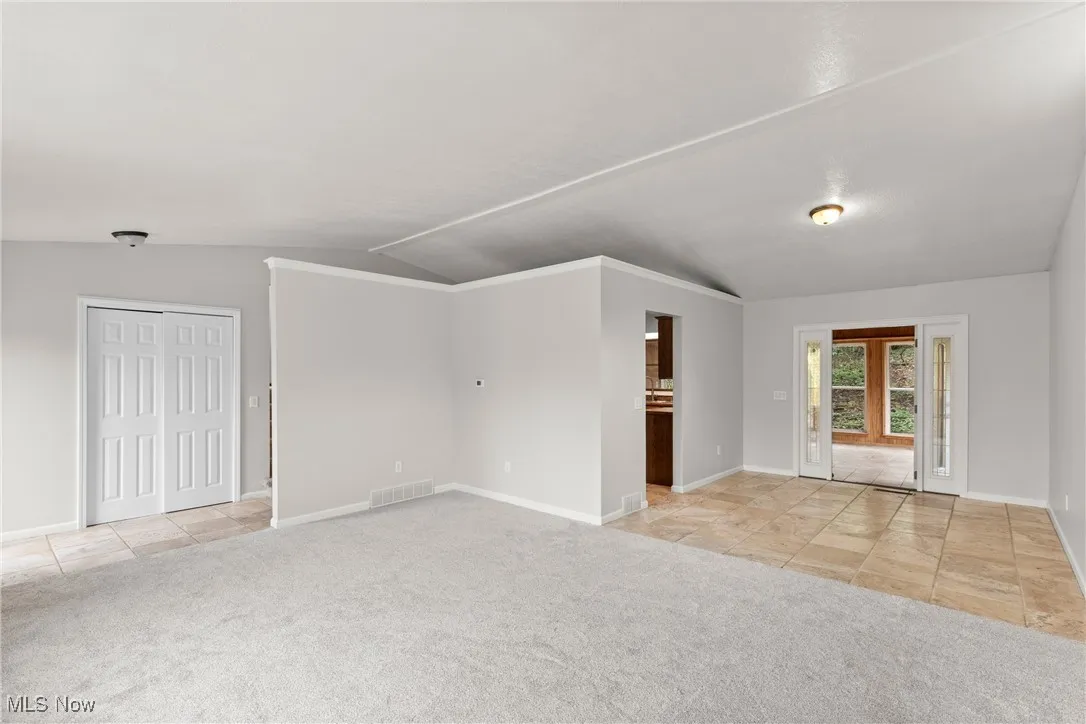 Living room featuring light carpet looking into dining area with tile floors