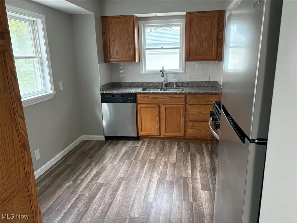 Kitchen featuring brown cabinetry, tasteful backsplash, appliances with stainless steel finishes, and light wood finished floors