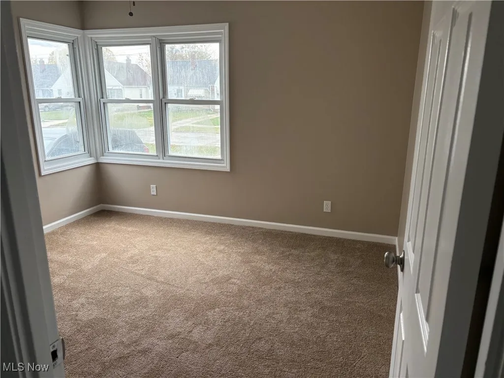Carpeted spare room featuring baseboards