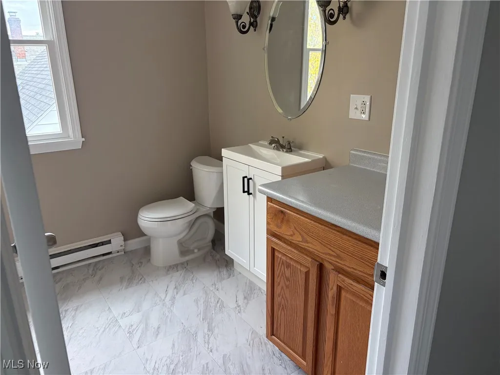 Half bath with a baseboard radiator and vanity