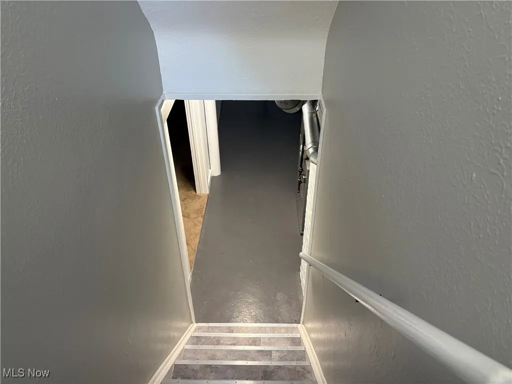 Stairs featuring a textured wall and baseboards