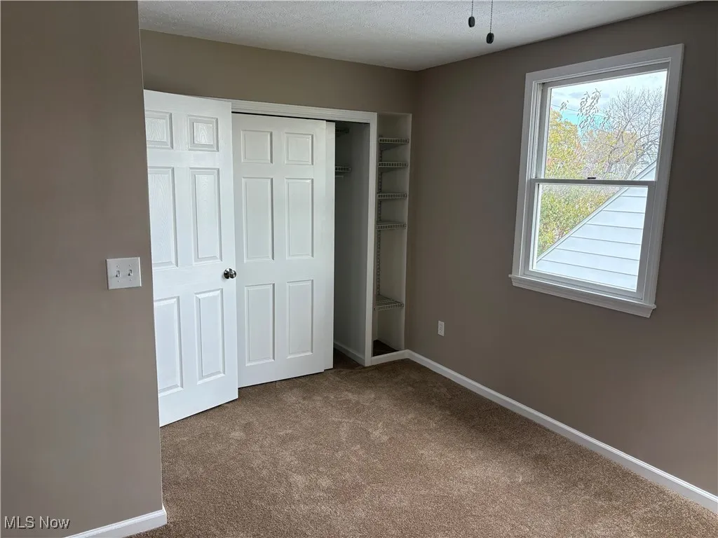 Unfurnished bedroom with carpet floors, a closet, and a textured ceiling