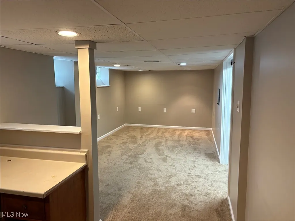 Below grade area with a drop ceiling, light carpet, and recessed lighting