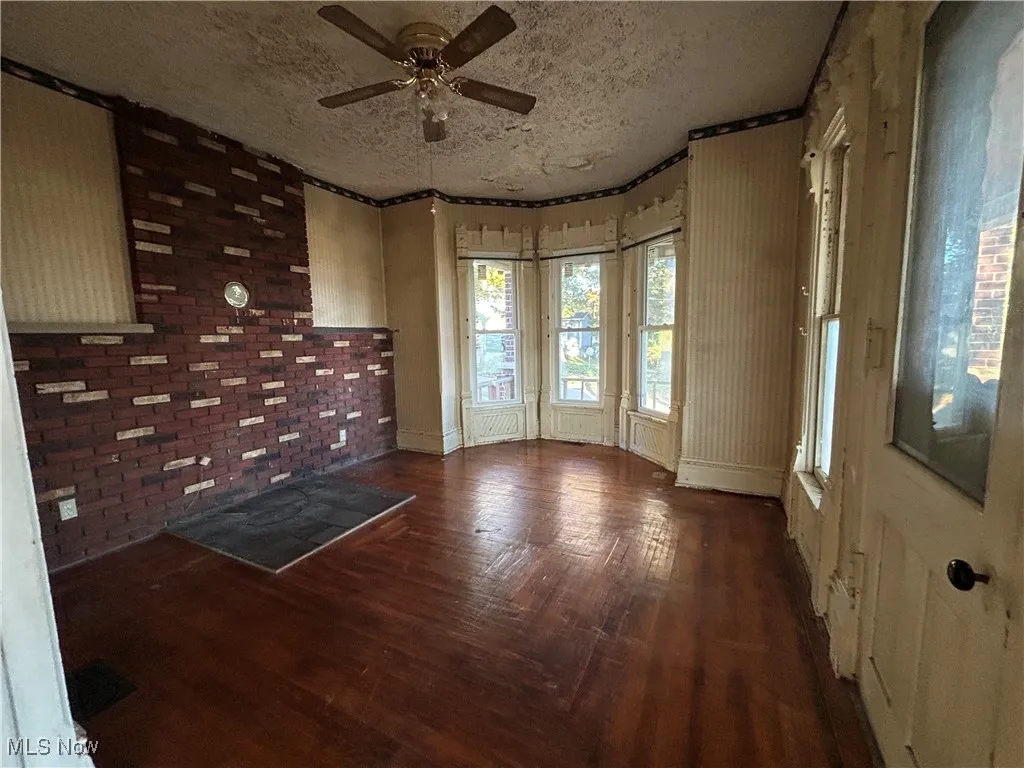 Unfurnished room with dark wood-type flooring, a ceiling fan, and a textured ceiling