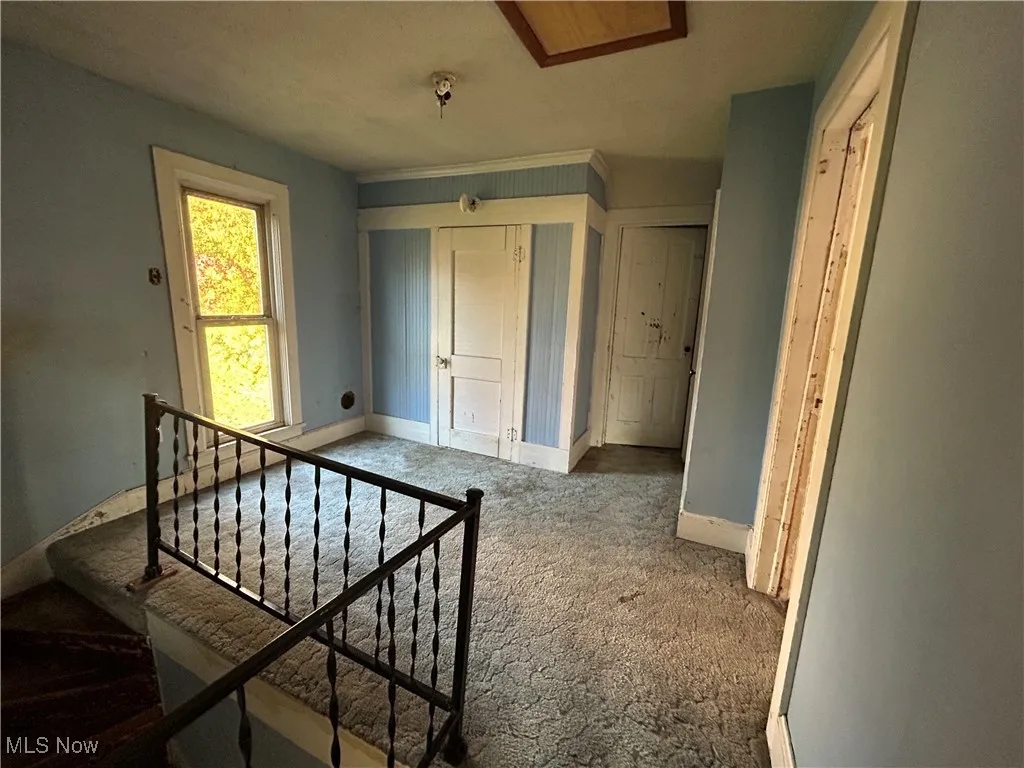 Hall featuring an upstairs landing and carpet flooring