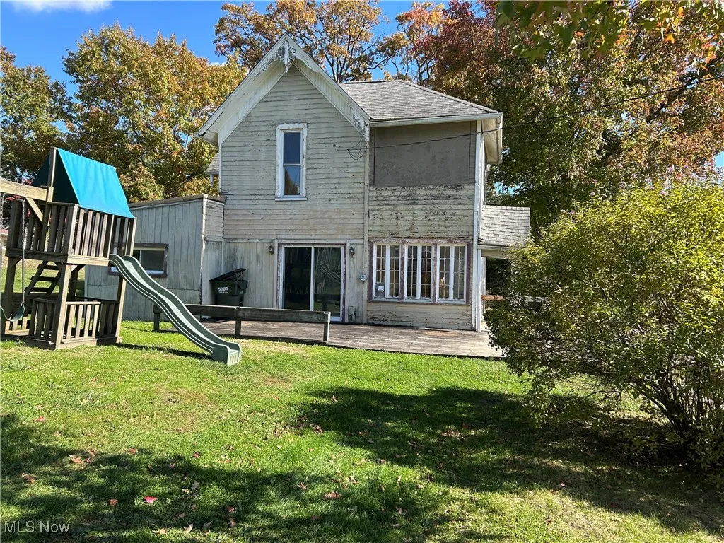 Side view of house with a yard, a playground, and a deck