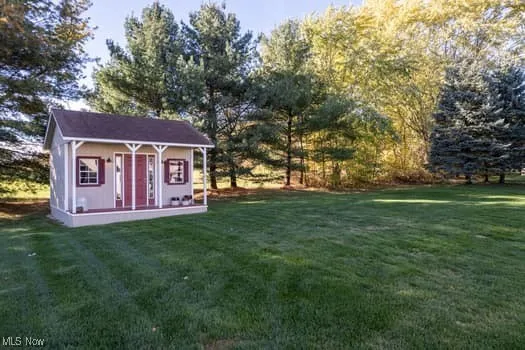 View of green lawn with a porch and an outdoor structure