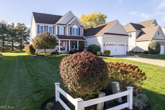 View of front of home featuring a front yard, covered porch, driveway, and an attached garage