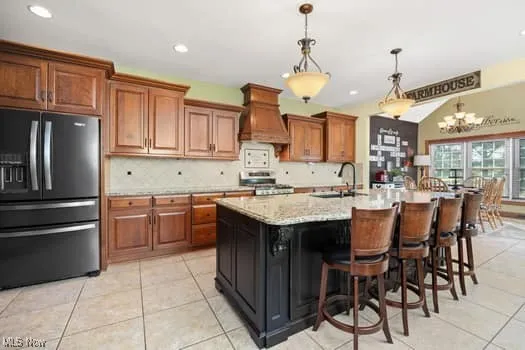 Kitchen featuring fridge with ice dispenser, decorative backsplash, decorative light fixtures, brown cabinetry, and recessed lighting