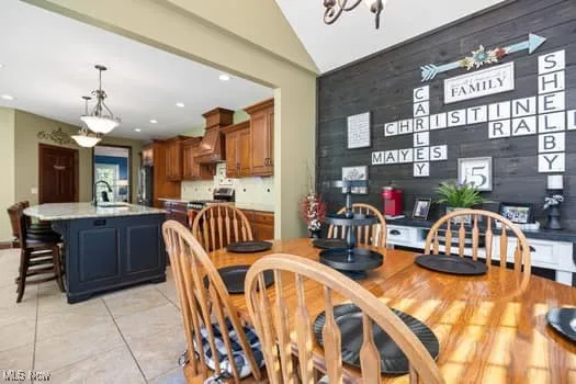 Dining room featuring vaulted ceiling, recessed lighting, light tile patterned floors, and a chandelier